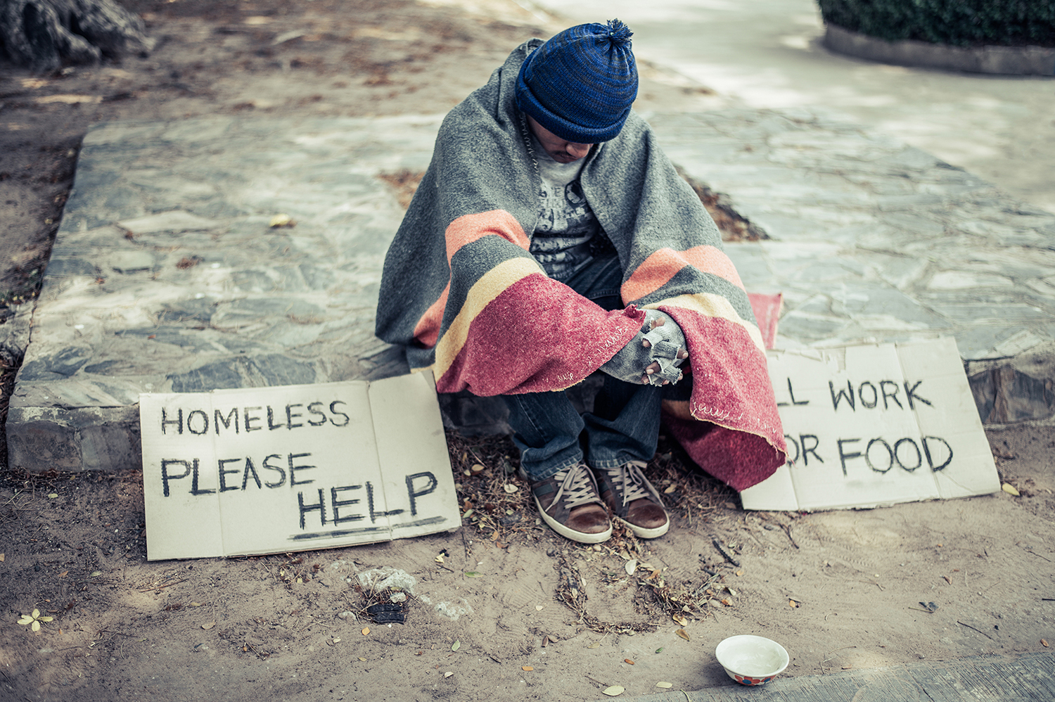 Beggars, wrapped in cloth, then wearing a hat and sitting down beside the road.